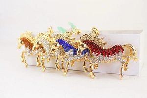 Detail of four horse-shaped metal keychains with sparkling rhinestones in assorted colors