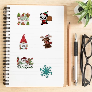 Flat lay of colorful Christmas stickers on a notebook featuring pandas, reindeers, and gnomes