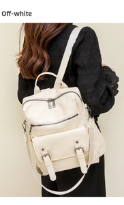 Model wearing a creamy white vintage PU leather backpack with tassel detail and buckles