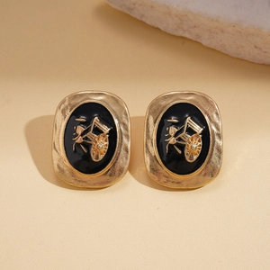 Détail de boucles d'oreilles vintage dorées avec émail noir et motif de calèche dorée