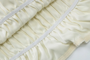 Detailed macro view of ivory chiffon fabric texture with elastic ruffled stitching details