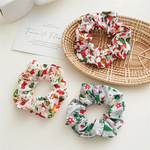 Three Christmas theme fabric scrunchies with Santa and reindeer patterns on white desk