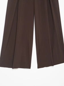 Dettaglio dei pantaloni larghi color caffè che mostra il drappeggio e il tessuto
