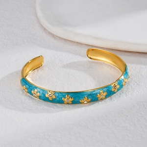 Elegant gold C-shaped open bracelet with blue enamel flower and sparkling rhinestone center