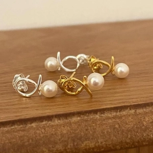 Macro shot of 925 sterling silver and gold pearl stud earrings on a wooden base