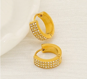 Detailed view of gold C-shaped hoop earrings with micro-paved white zircons on fabric
