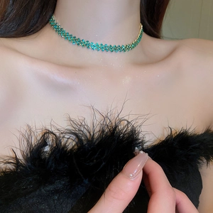 Dettaglio della collana choker a due strati con strass verdi sul collo del modello