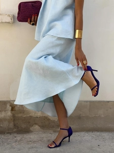 Detail of light blue linen two-piece set featuring a flowing fishtail skirt and purple heels