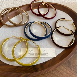 Detailed view of flocked geometric hoop earrings in assorted autumn colors with gold lining