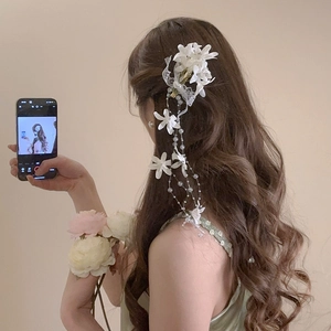 Close-up of white fabric flower hair clip with elegant pearl tassel and lace detail