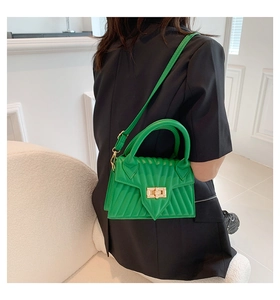 Detail of green quilted handbag with golden twist lock and wave texture on a black suit