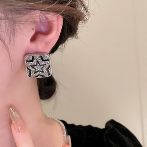 Close-up of square star stud earring with black enamel and micro-pave crystals
