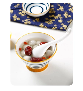 Detail of blue striped ceramic spoon and soup bowl with tangyuan and red dates