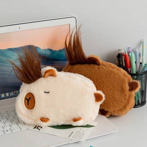 Close-up of beige and brown plush capybara stationery bags on a wooden study desk