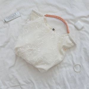 Close-up of floral embroidery on cream canvas tote bag with orange rope handle and metal clasp