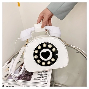 Close-up of retro white telephone bag with vintage rotary dial and handset handle detail