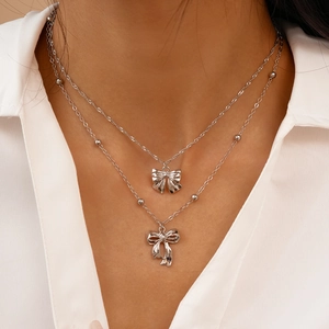 Gros plan d'un collier argenté à double épaisseur avec pendentifs nœuds élégants