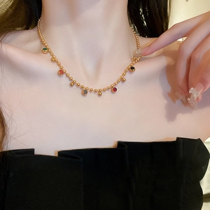 Close-up of gold beaded necklace with colorful round pendant charms on female model