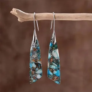 Detail of bohemian teardrop earrings with colorful stone mosaic on a natural wood branch