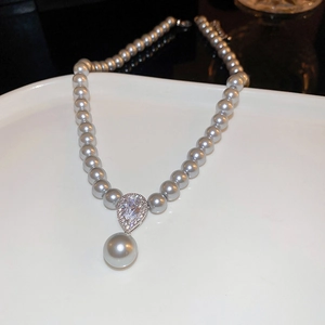 Close-up of double-layer pearl necklace with a shimmering pavé teardrop pendant