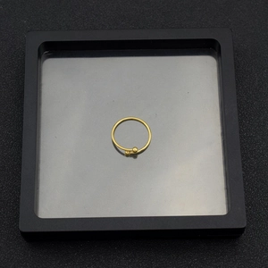 Detailed top view of a minimalist gold open ring with small metal beads in a black display box