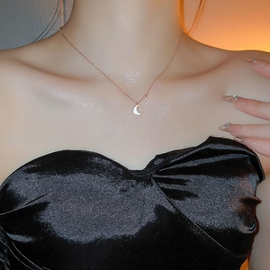Détail d'un collier ras du cou en or rose avec croissant de lune et étoile sur un modèle