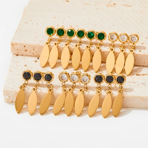 Detail of gold fringe earrings with zircon inlay and leaf-shaped metal pendants