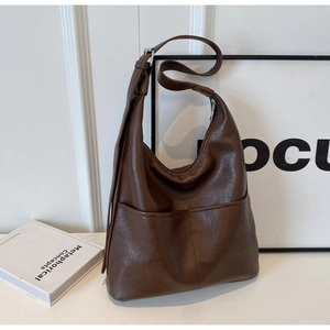Detail of dark brown faux leather hobo bag with front pockets and adjustable strap