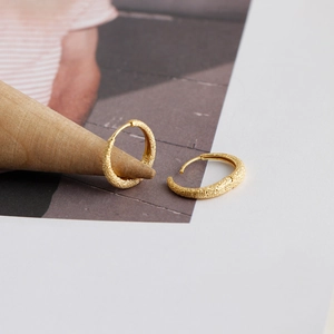 Detailed macro view of S925 sterling silver hoop earrings with a gold sandblasted texture