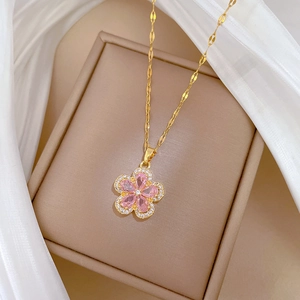 Close-up of gold flower necklace with pink crystal petals on beige jewelry box with silk