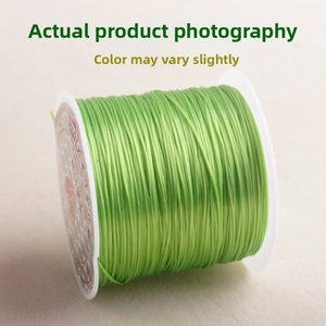 Detail view of vibrant green crystal elastic cord on white spool for jewelry making