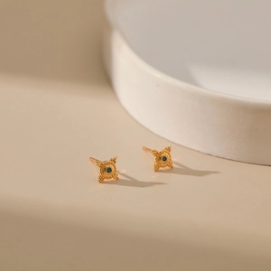 Detailed macro of 18K gold plated brass stud earrings with a central blue gemstone