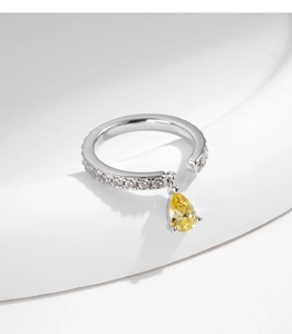 Macro view of silver ring featuring a sparkling pear-cut yellow gemstone drop charm