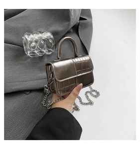 Detail of silver crocodile pattern mini bag with metallic top handle and chain strap
