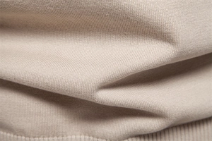 Vue macro détaillée montrant la texture douce du tricot de coton et le tissage du pull beige
