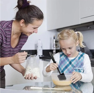 A young girl uses the black silicone meat chopper to mix ingredients in a family kitchen