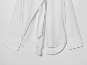 Détail de l'ourlet incurvé et des poignets plats de cette chemise blanche en coton à manches