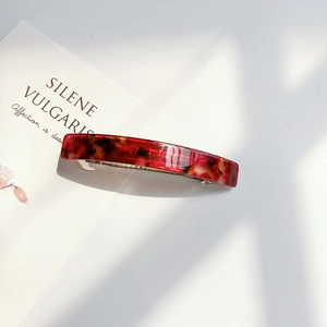 Detail of red tortoise shell acrylic hair clip with metallic spring for women