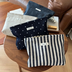Macro view of four assorted canvas cosmetic bags featuring dots, stripes, and solid patterns