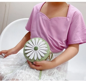 Detail of light green daisy round crossbody bag on a child model with PU leather finish