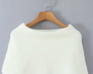 Close-up of the delicate white knitted texture and off-shoulder neckline on a hanger