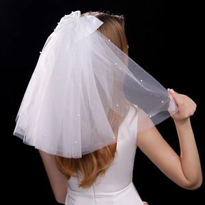 Detail of white bridal veil with large silk bow and scattered elegant pearls