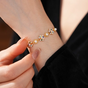 Detailed close-up of a vintage floral bracelet with pearls and colored zircons on wrist
