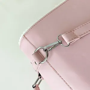 Detail of silver D-ring and lobster clasp hardware on a premium pink leather bag