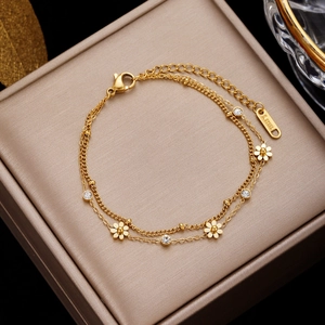 Double-layered gold daisy bracelet with zircon charms on a luxury jewelry box display