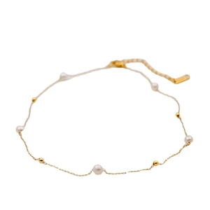 Minimalist gold titanium necklace with fresh water pearls on a clean white background