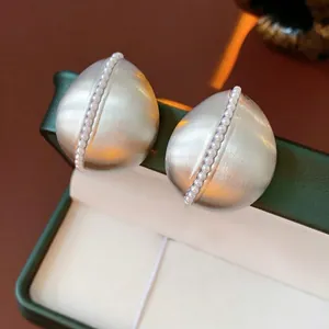 Matte silver teardrop earrings with white pearls on green jewelry box 45-degree view