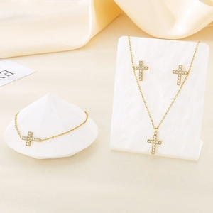 Detailed view of a gold cross jewelry set with sparkling rhinestones on silk fabric