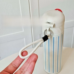 Detail of portable woven strap with metal buckle on white striped insulated water bottle