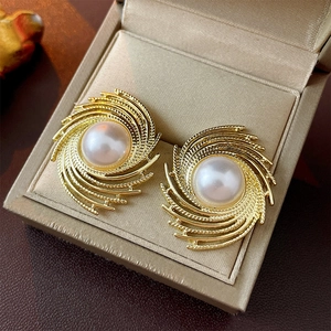 Elegant gold metal spiral earrings with central white pearls in luxury gift box display